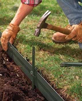 metal lawn edging installation using a hammer to pound down stakes