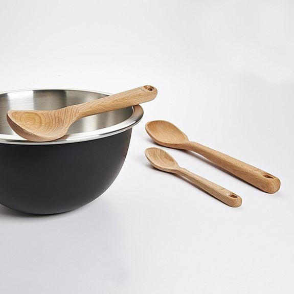 Three wooden spoons, two lined up on the left and the largest on the left on top of a metal pot
