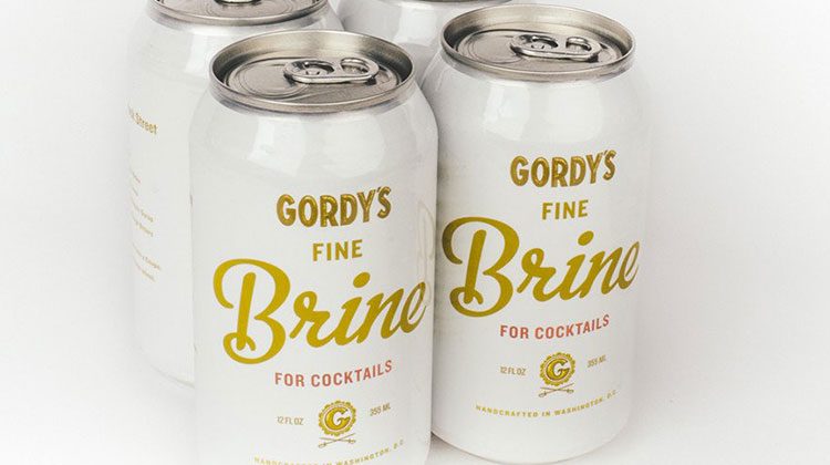 Four pack of cans that are white with gold letterings identifying it as Gordy's Fine Brine for Cocktails
