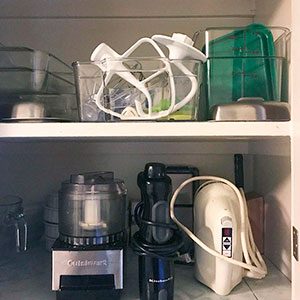 Clear bins in a cabinet holding and dividing appliances and accessories