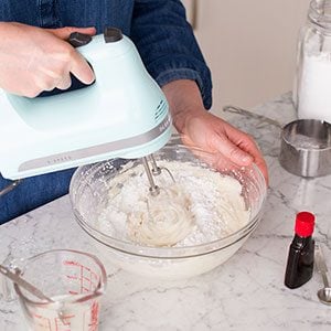 Person using a hand mixer to beat together butter and other ingredients