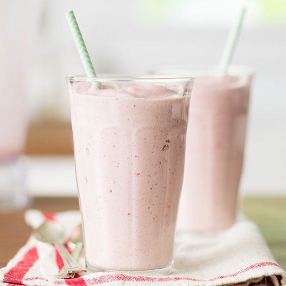 Strawberry milkshake in a glass with a green striped straw sticking out