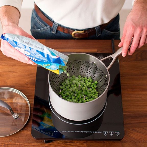 Person pouring peas from a bag into a metal pot