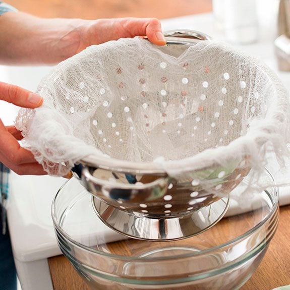 Strainer inside another bowl and with two layers of cheese cloth over top