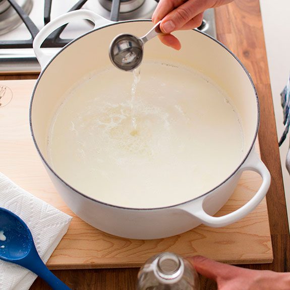 Mixture bubbling in a Dutch oven, removed from heat while a person gently stirs in vinegar