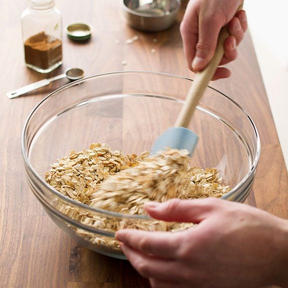 person stirring dry ingredient together in a glass bowl with a spatula