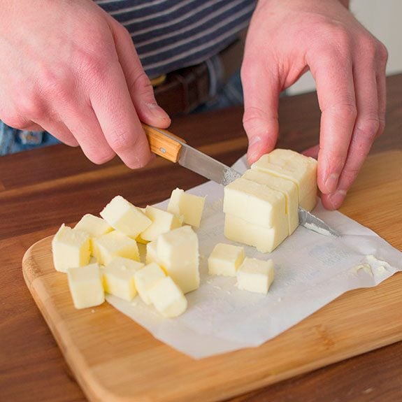 person cutting a stick of butter into even cubes to show how to soften butter quickly