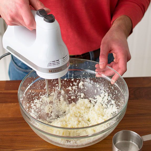 person using a hand mixer to blend together the wet ingredients