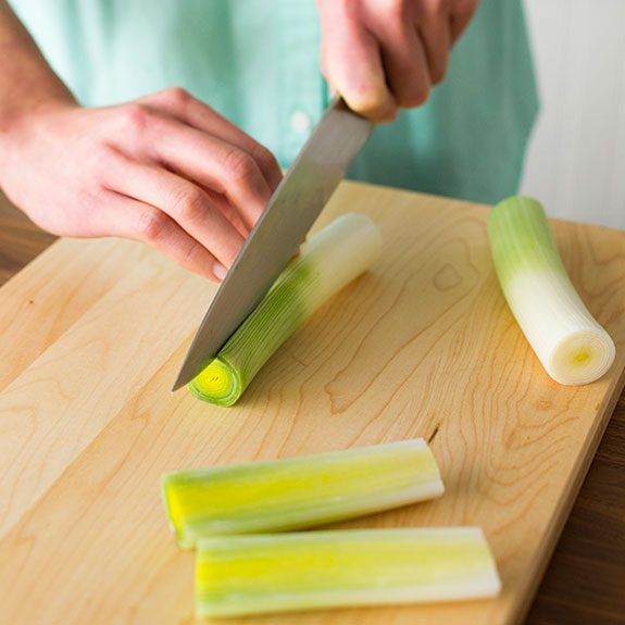 person slicing the leeks down the middle with a knife