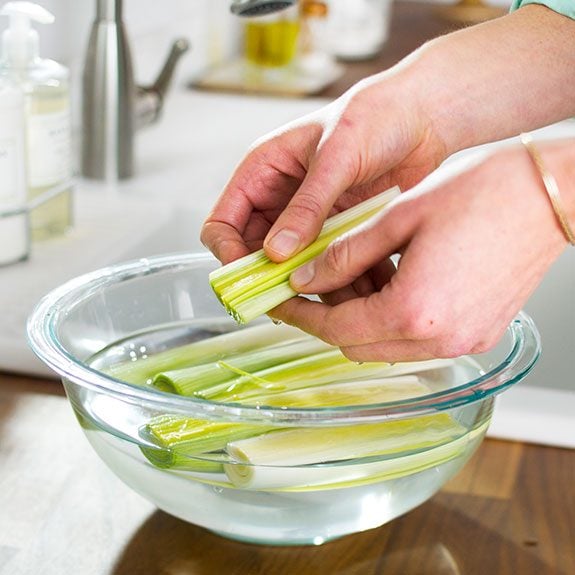 rinsing the halved leeks in a glass bowl filled with water