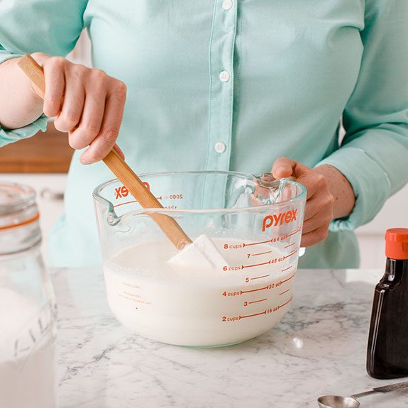 person stirring ingredients together in a large glass bowl