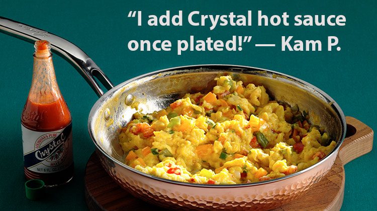 Scrambled eggs in a skillet with a bottle of hot sauce on the side and the words 'I add Crystal hot sauce once plated!' -- Kam P.