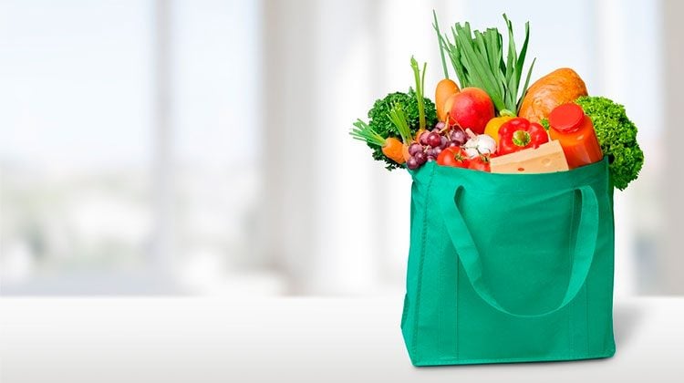 green tote bag filled with different produce and nearly overflowing