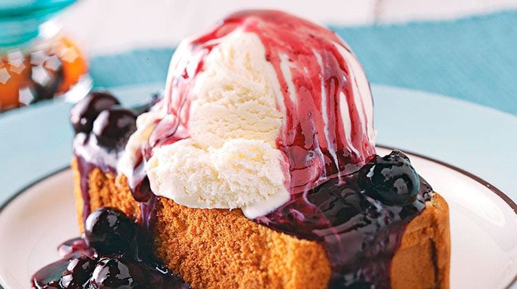ice cream sitting on top a slice of pound cake with blueberry sauce poured over both