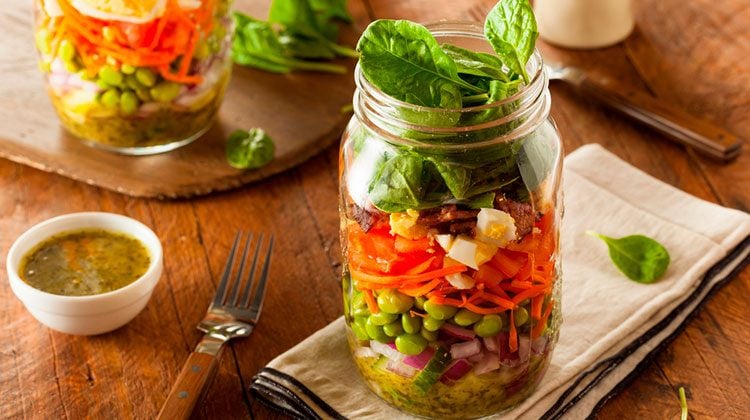 two large glass jars filled to the top with layers of different vegetables