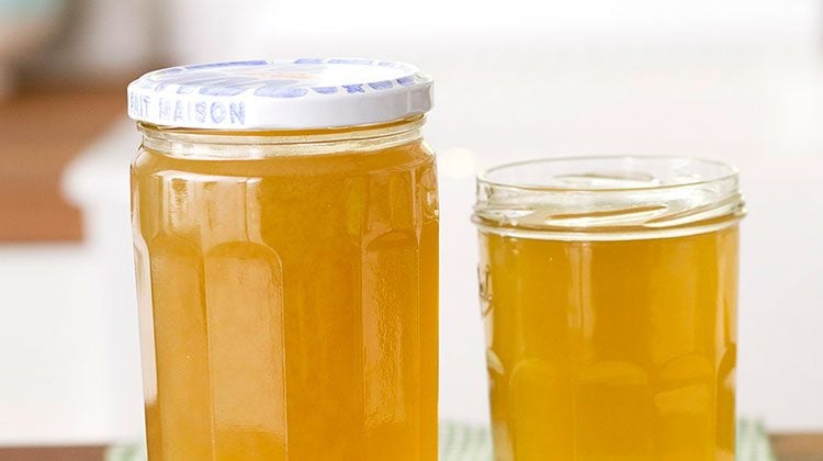 Two glass jars of vegetable broth side-by-side, one with a lid and one without