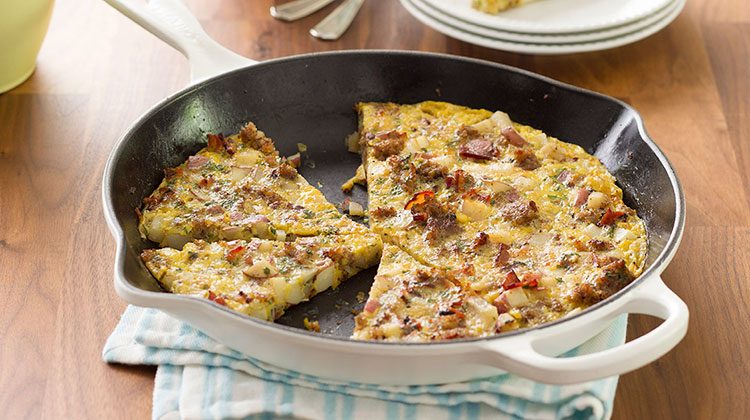 Frittata in a skillet sliced with pieces missing