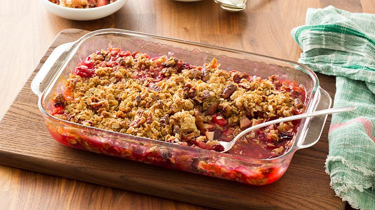 Fruit crisp in a 13x9 glass pan on a wooden cutting board on top a wooden tabletop