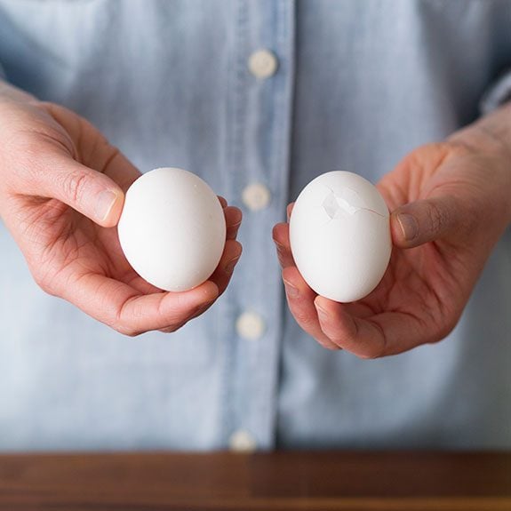 Person holding an egg in each hand and presenting them to the viewer to show the growing cracks in their sides