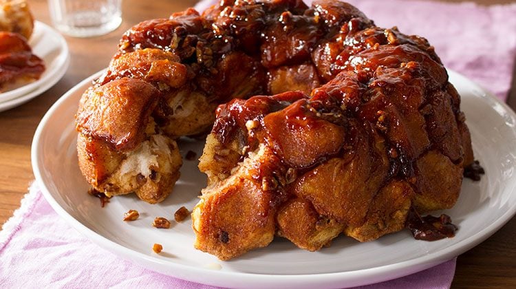 Monkey bread on a white plater with a slice already taken out of the front