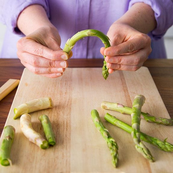 person is gently bending a stalk of asparagus between both their hands