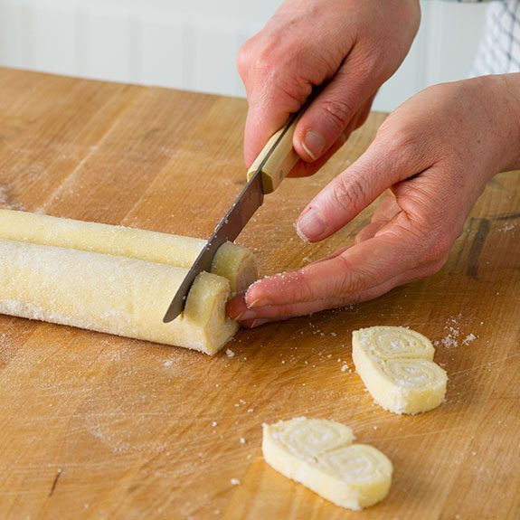 person slicing the rolled up dough with a knife