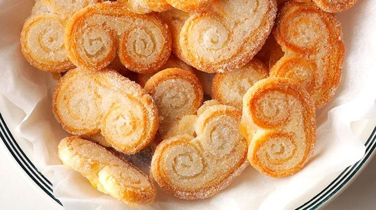 palmiers piled onto a white plate with several stripes around the rim